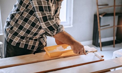 Man painting a piece of wood white indoors